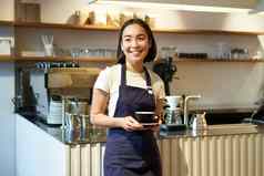 肖像亚洲微笑女咖啡师咖啡馆女服务员持有杯咖啡服务客户采取订单平板电脑站咖啡馆计数器