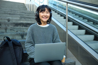 女学生作品项目远程坐在楼梯<strong>街</strong>作品移动PC听音乐耳机微笑