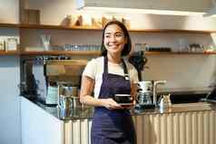 肖像亚洲微笑女咖啡师咖啡馆女服务员持有杯咖啡服务客户采取订单平板电脑站咖啡馆计数器