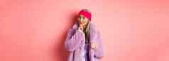 时尚购物概念时尚的亚洲夫人紫色的人造革外套感兴趣感兴趣促销活动微笑思考粉红色的背景
