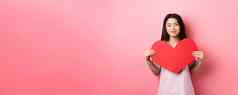 情人节一天概念可爱的十几岁的亚洲女孩显示大红色的心卡下降爱浪漫的日期衣服微笑温柔的相机粉红色的背景