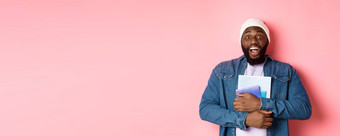 图像成人非裔美国人男人。持有笔记本电脑微笑研究课程站粉红色的背景