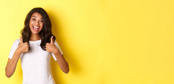 肖像可爱的快乐的非裔美国人女孩显示竖起大拇指支持同意赞扬优秀的工作站黄色的背景