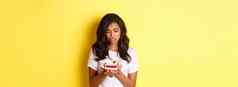 图像伤心非裔美国人女孩一块蛋糕吃饮食站黄色的背景