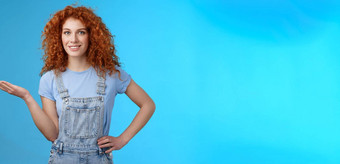 显示很酷的产品有吸引力的快乐的自信红色头发的人女模型卷曲的发型现在<strong>客户</strong>对象持有棕榈空白蓝色的复制空间广告站蓝色的<strong>背景</strong>
