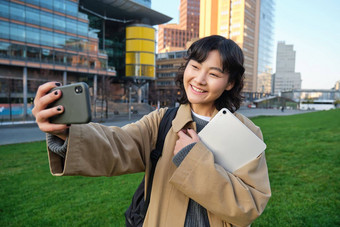 快乐大学学生朝鲜文女孩需要自拍论文数字平板电脑持有智能手机提出了大学校园