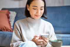 肖像微笑亚洲女人坐在首页智能手机应用程序订单交付消息移动电话应用程序