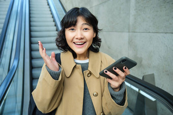 快乐并亚洲女孩惊讶快乐的持有智能手机自动扶梯很高兴脸赢了听到好新闻