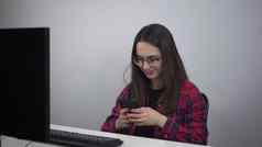 年轻的女人聊天智能手机工作场所办公室专家眼镜红色的衬衫电话手