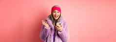 在线购物时尚概念亚洲成熟的女人兴奋检查互联网促销提供智能手机快乐相机粉红色的背景