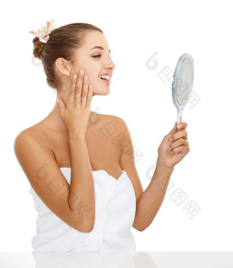 护肤品例程工作华丽的年轻的女人欣赏脸镜子白色背景