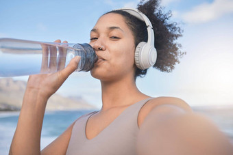 女人跑步者喝水自拍音乐户外锻炼锻炼健身黑色的女人耳机海滩培训健康健康自然海洋夏天太阳
