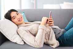 年轻的人肖像快乐的年轻的女人浏览手机放松沙发首页一天
