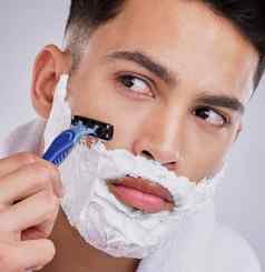 好剃须刀帮助防止缺口削减年轻的男人。剃须胡子工作室背景