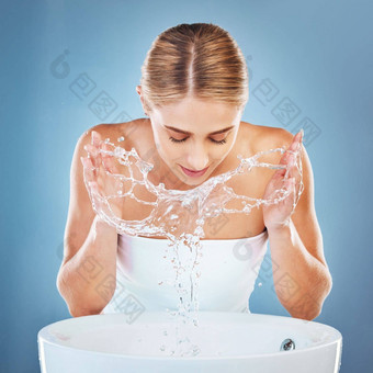 女人水洗脸梳理<strong>护肤品蓝色</strong>的背景工作室水槽盆地美模型湿面部清洁水飞溅卫生维护医疗保健健康