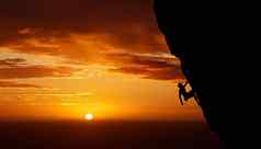 攀爬山日落轮廓男人。体育锻炼健身岩石培训自然锻炼旅行加拿大运动员自由橙色日落天空背景