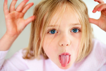 淘气的年轻的女孩显示舌头特写镜头肖像淘气的年轻的女孩显示舌头