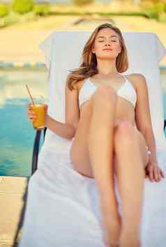 懒惰的天夏天有吸引力的年轻的女人享受在游泳池边喝