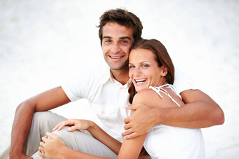 爱的拥抱快乐年轻的夫妇拥抱坐着海滩