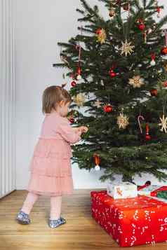 垂直照片婴儿女孩粉红色的衣服把饰品圣诞节树