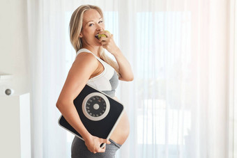 婴儿值得健康的开始生活肖像快乐怀孕了女人穿着运动服装携带规模吃苹果首页