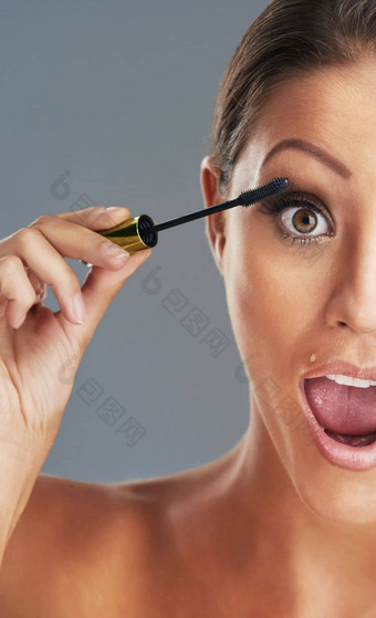 睫毛爱睫毛膏工作室肖像美丽的年轻的女人把睫毛膏灰色背景