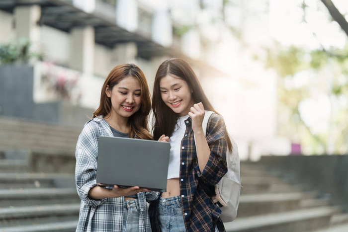 美丽的年轻的亚洲女人大学学生朋友在户外大