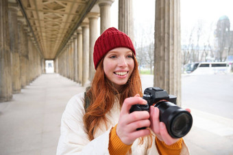 年轻的红色头发的人女摄影师使生活方式拍摄城市中心需要照片微笑完美的拍摄使图片