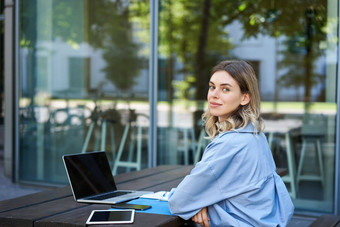 肖像年轻的女商人工作移动PC坐着在户外企业女人视频闲谈，聊天会议