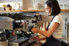 快乐微笑酒保咖啡师咖啡机准备订单使卡布奇诺咖啡拿铁穿蓝色的围裙