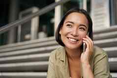 肖像亚洲女孩微笑会谈移动电话年轻的女人调用朋友坐着楼梯