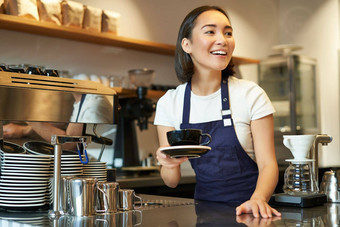 肖像美丽的亚洲女孩学生工作<strong>兼职</strong>咖啡馆持有杯咖啡使订单客户端穿统一的