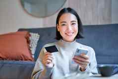 肖像微笑朝鲜文女人信贷卡智能手机应用程序支付购买订单在线交付