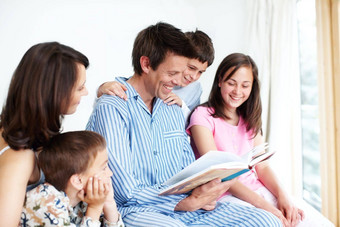 父母显示孩子们<strong>快乐阅读</strong>爱的家庭<strong>阅读</strong>床上
