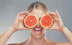 女人手水果眼睛护肤品持有葡萄柚健康的健康灰色工作室背景快乐女美化妆品多汁的水果微笑维生素营养