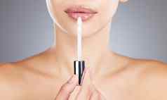 女人嘴唇唇光泽应用程序美化妆发光护肤品健康灰色背景工作室模型口红工具刷化妆品皮肤病学发光奢侈品沙龙产品
