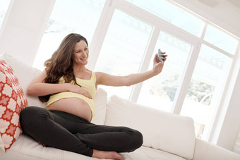自拍<strong>好友</strong>董事会年轻的怀孕了女人采取自拍手机生活