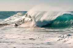 冲浪者骑巨大的波追逐日落
