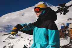 肖像专业滑雪橙色滑雪护目镜站滑雪板肩膀背景白雪覆盖的山滑雪度假胜地