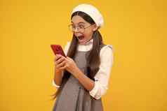 兴奋少年女孩聪明的电话分享社会媒体聊天移动电话穿时尚的休闲时尚的衣服孤立的黄色的背景孩子智能手机