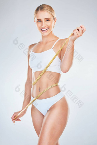 <strong>减肥</strong>法健康女人磁带腰动机健身健康培训灰色工作室背景快乐微笑肖像模型测量胃