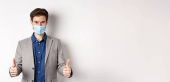 科维德流感大流行业务概念快乐的男人。西装医疗面具预防措施办公室显示拇指白色背景