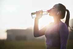 健身日落女人喝水瓶培训锻炼锻炼户外有氧运动运行渴了年轻的运动员体育水合作用营养健康健康的身体能源