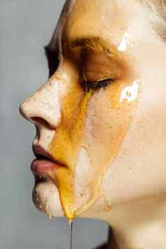 美丽的年轻的浅黑肤色的女人女人雀斑应用蜂蜜脸美治疗