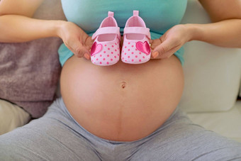 孩子们小脚离开大的足迹特写镜头拍摄怀孕了女人持有一对粉红色的婴儿<strong>鞋</strong>子肚子<strong>首页</strong>