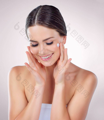 分享护肤品秘密滋润工作室拍摄美丽的年轻的女人应用保湿霜脸灰色背景