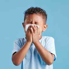 拉美裔男孩吹鼻子组织蓝色的工作室背景孩子感觉生病的流感病毒感染痛苦流鼻涕的鼻子