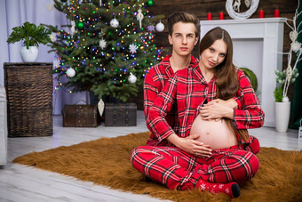 怀孕了女人坐在地毯男人。坐在回来拥抱