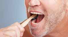 清洁口手刷牙牙齿牙科牙膏健康的口服卫生梳理工作室生态友好的变焦高级男人。自然竹子木牙刷牙齿美白