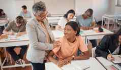 老师学生教室测试知识学习更高的教育年轻的女黑色的女人教育家帮助学生考试会说话的学生写作笔记书焦点
